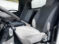 Interior view of a 2016 Isuzu NQR showing two gray cloth seats in the foreground