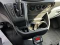 The interior console of a 2015 Ford Transit featuring gear shift, climate control knobs, and cup holders along with a digital display panel