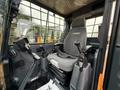 Interior of a 2022 Hyundai R55-9A excavator featuring a gray seat with armrests and joysticks for operation