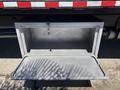 A metal storage compartment with a diamond pattern design attached to a truck open and empty inside