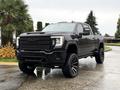 A black 2022 GMC Sierra 3500HD with a rugged appearance large tires and a bold front grille positioned at an angle