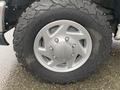 Close-up of a tire on a 2011 Ford Econoline featuring a silver alloy wheel with a rugged tread pattern
