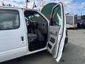 A 2009 Ford Econoline van with an open side door revealing the driver's seat and dashboard