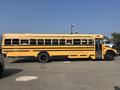 A 2007 Blue Bird Vision school bus with a yellow exterior and black stripes parked in a lot