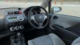 Interior of a 2006 Honda Fit featuring a dashboard with control knobs and a steering wheel with the Honda logo