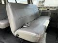 A gray leather bench seat from a 2004 Ford Econoline van with seatbelts and a simple design