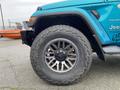 A blue 2020 Jeep Wrangler Sahara with large, rugged tires and a distinctive rim design