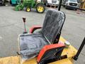 A black seat with red armrests is prominently displayed on a yellow mini loader with a protective plastic cover on the seat