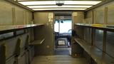 Interior view of a 2011 Ford Econoline showing empty shelves along the sides and a driver's seat visible at the front