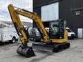 A yellow Caterpillar 306 excavator with a black bucket and tracks is prominently displayed in the foreground
