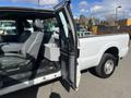 A 2013 Ford F-250 SD with an open door showing the interior featuring gray seats and a console