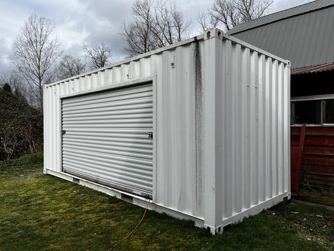 A 40 foot storage container featuring a roll-up door primarily made of metal with a white exterior surface