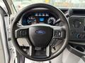 Steering wheel of a 2022 Ford Econoline featuring the Ford logo and controls for audio and cruise settings
