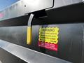 A 2021 Ford F-550 truck with a warning label about the tailgate latch and a yellow handle for operation