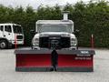 A 2011 Ford F-550 truck equipped with a large red snow plow attached to the front