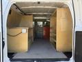 Interior view of a 2011 Ford Econoline van featuring wooden shelves and a workbench arranged along the sides of the cargo space