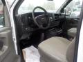 Interior view of a 2011 Chevrolet Express showing the driver's seat dashboard and steering wheel with a gray fabric seat and controls
