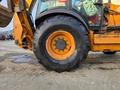 A 2015 Case 590SN backhoe loader with a large black tire in the foreground showcasing its rugged tread and tire rim