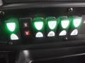 Control panel with multiple switches and indicator lights in a 2016 Chevrolet Express displaying green light indicators for various functions