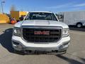 A 2018 GMC Sierra 1500 in white with a prominent black grille displaying the GMC logo and chrome accents