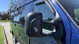 A blue 2013 Ford Econoline van with a roof rack and a side mirror visible in the foreground