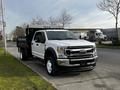 A white 2021 Ford F-550 with a dump bed parked on the side of the road