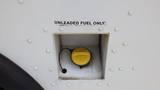 A fuel filler neck with a yellow cap labeled for unleaded fuel only