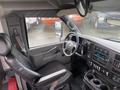 Interior view of a 2018 Chevrolet Express showing the driver's seat dashboard and steering wheel with various control buttons and cup holders