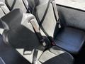 Two gray leather seats with seatbelts inside a vehicle