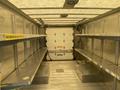 Interior of a 2012 Ford Econoline with metal shelving units on both sides and a rear garage door