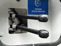 Image of two black levers labeled as engine accelerator located in the foreground of a machinery control panel