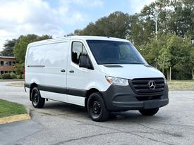 A 2021 Mercedes-Benz Sprinter van in white with a black front grille and wheels parked at an angle