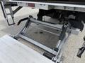 A metal loading ramp mechanism of a 2022 International MV607 featuring hydraulic lift arms and a steel frame for transporting cargo