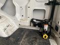 A hydraulic jack positioned inside the cargo area of a 2011 Ford Econoline with a textured black rubber floor mat