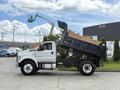 A 2017 Ford F-750 dump truck with a raised bed, displaying a white body and black dumping compartment, is shown in profile.