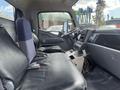 Interior view of a 2008 Mitsubishi Fuso FE180 showing two black leather seats with one partially upholstered in blue fabric and a dashboard with visible controls and equipment