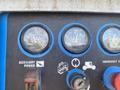Control panel of a 1997 Genie S-65 4X4 featuring gauges for water temperature oil pressure and voltage with labeled buttons for auxiliary power and emergency stop
