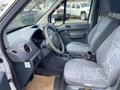 Interior view of a 2013 Ford Transit Connect showing the driver's seat and passenger seat with gray patterned upholstery and a steering wheel