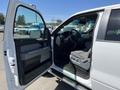 A 2014 Ford F-150 with an open driver's side door showing the interior and dashboard with fabric seats and a steering wheel