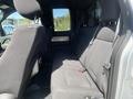 Interior view of a 2014 Ford F-150 showing the backseat area with fabric upholstery and seatbelts attached to the seats