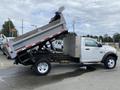 A white 2011 Dodge Ram 5500 dump truck with its bed tilted up, revealing a flatbed and a silver storage box on the side