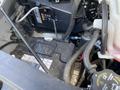 Close-up of the engine compartment of a 2023 GMC Savana showing the car battery various cables and connectors in the foreground