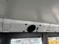 The interior of a 2007 Freightliner B2 school bus showing the ceiling, emergency exit sign, and a round speaker mounted above the door