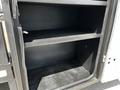An empty storage compartment inside a 2016 Ford F-550 with two shelves and a black interior