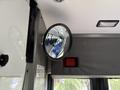 A round mirror mounted inside a vehicle reflecting empty seats and an interior view of a 2020 Chevrolet Express