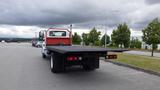 A 2015 International DuraStar 4300 flatbed truck parked with its flatbed extended and rear lights visible