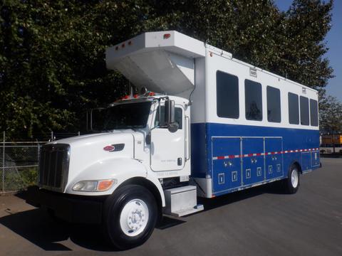 A 2008 Peterbilt PB340 truck with a white and blue color scheme featuring multiple windows and a raised roof designed for passenger transport