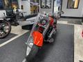 A 2024 Harley Davidson Fat Boy motorcycle with a shiny chrome finish and a bold red front fender positioned in a showroom