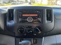 The dashboard of a 2017 Nissan NV200 featuring a radio display climate controls and a gear shift area