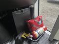 A red emergency kit is positioned next to a fire extinguisher on the floor of a Chevrolet Express vehicle